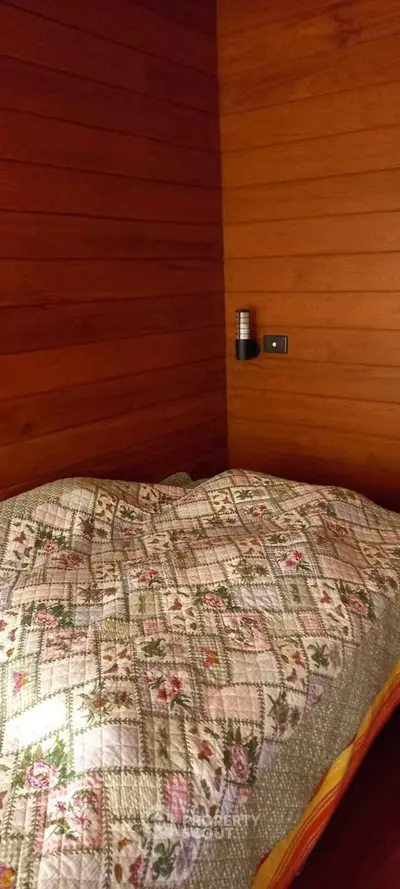 Cozy wooden bedroom with floral quilt, perfect for a rustic retreat.