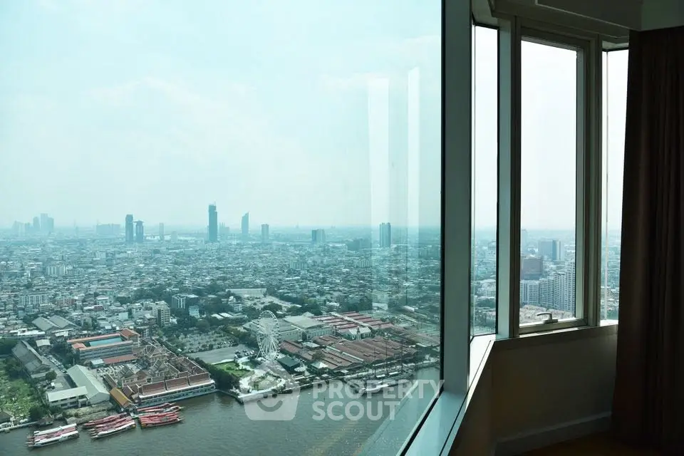 Stunning high-rise cityscape view from a modern apartment window overlooking a river.