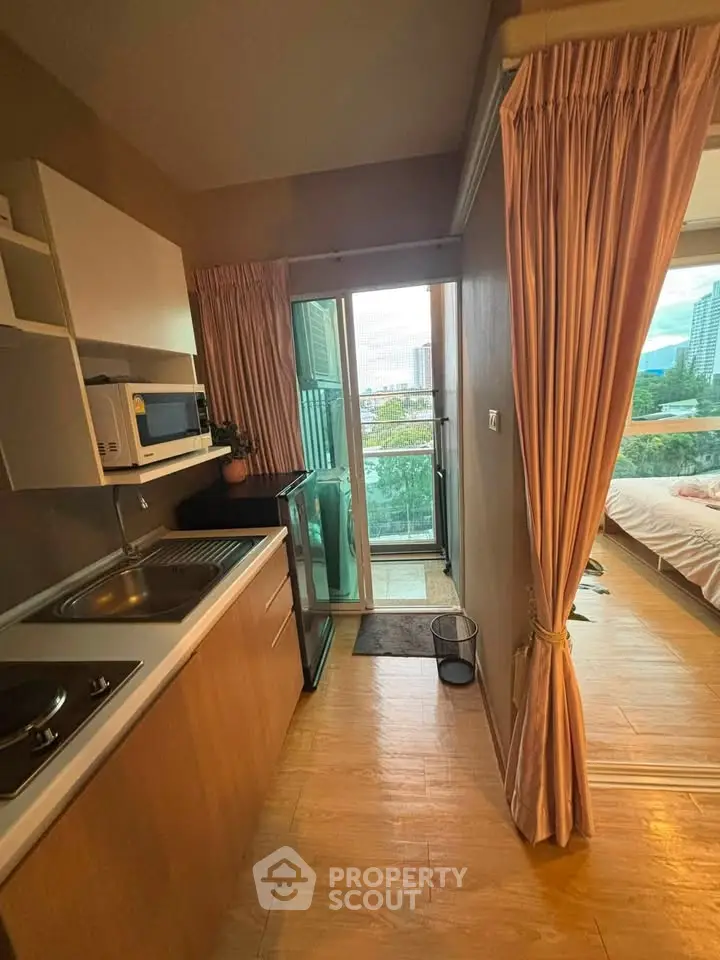 Charming compact kitchen with balcony access and city view, featuring modern appliances and cozy wooden flooring.