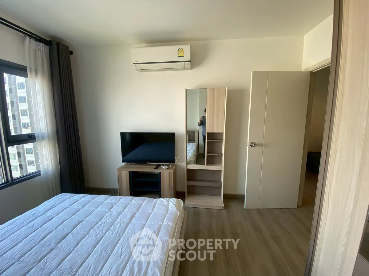 Modern bedroom with air conditioning, TV, and wooden furniture in a bright apartment.