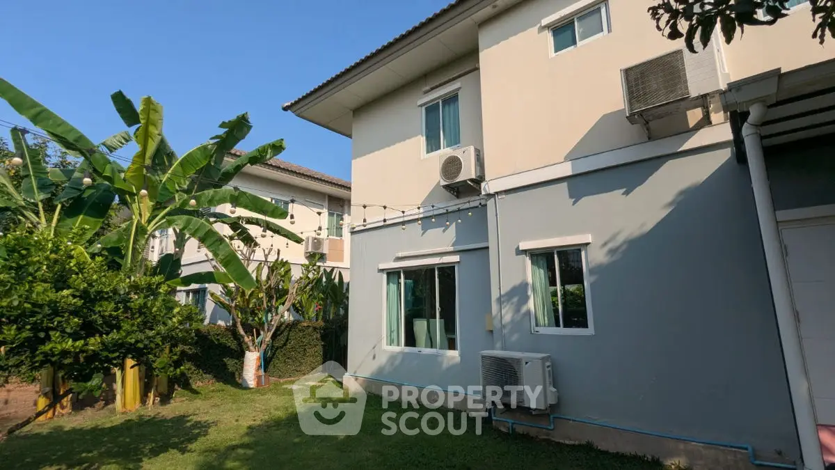 Charming two-story home with lush garden and modern air conditioning units, perfect for family living.