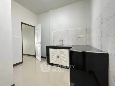 Modern minimalist kitchen with sleek black countertops and white cabinetry in a compact space.
