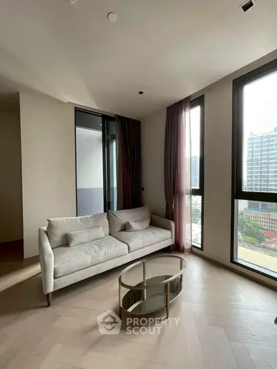 Modern living room with large windows and stylish furniture in urban apartment.