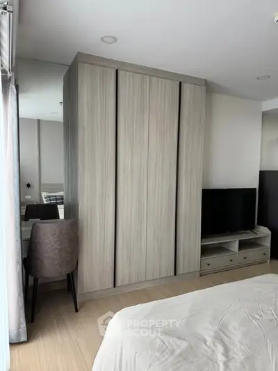 Modern bedroom with sleek wardrobe and TV unit, featuring a cozy study nook.
