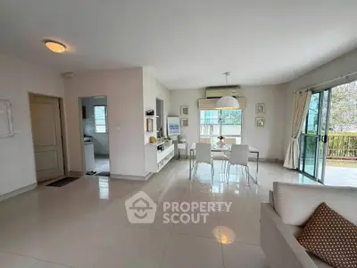 Spacious open-plan living and dining area with modern decor and large windows.