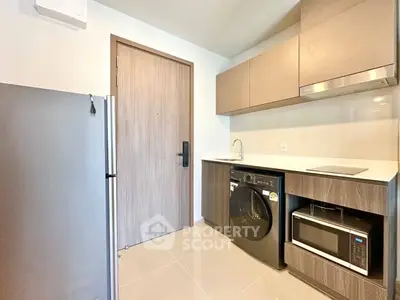 Modern kitchen with sleek appliances and minimalist design, featuring a washing machine and microwave.