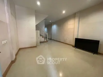 Spacious empty room with staircase and modern lighting, ideal for customization.