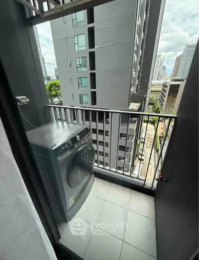 Compact balcony with washing machine and city view in modern apartment building.
