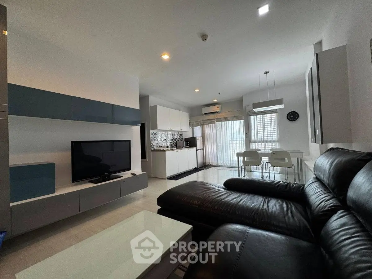 Modern living room with sleek leather sofa and open kitchen layout