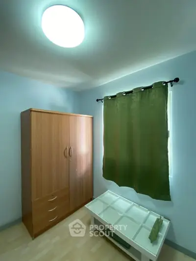 Cozy bedroom with wooden wardrobe and green curtains, perfect for minimalist living.