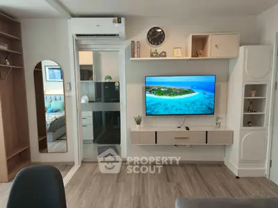 Modern living room with sleek TV setup and stylish decor, featuring a glimpse into a cozy bedroom.