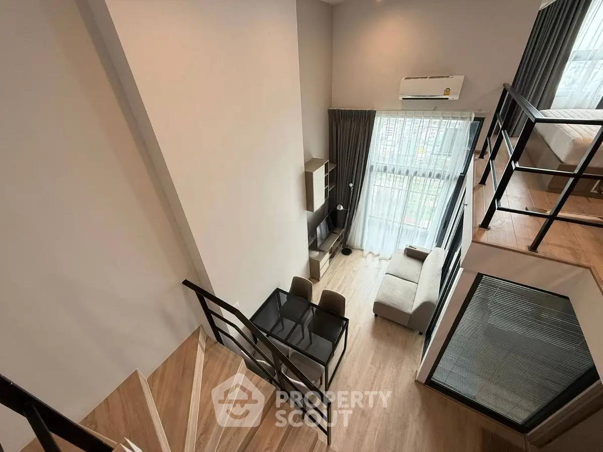Modern loft apartment with mezzanine, stylish living area, and large windows for natural light.
