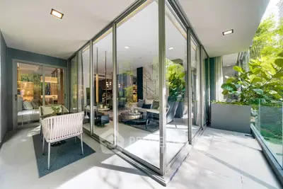 Luxurious modern living room with floor-to-ceiling glass walls and lush garden view.