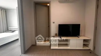 Modern apartment interior with sleek TV stand and cozy bedroom view.