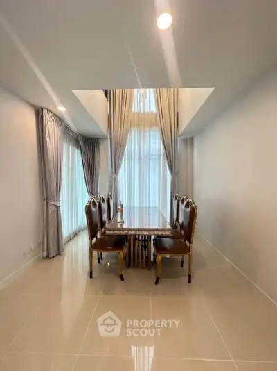 Elegant dining area with high ceiling and luxurious curtains in modern home.