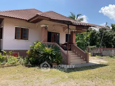 Charming single-story house with a tiled roof and lush garden, perfect for serene living.