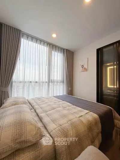 Cozy bedroom with large window and elegant curtains, perfect for relaxation and comfort.