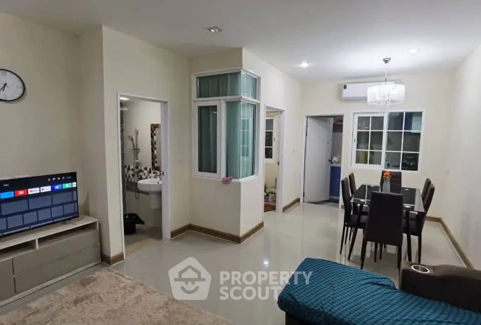 Modern living room with dining area and TV, featuring sleek furniture and bright lighting.