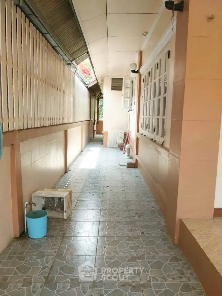 Spacious outdoor corridor with tiled flooring and natural light, perfect for relaxation or utility use.