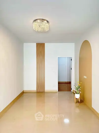 Elegant minimalist interior with modern chandelier and decorative wall accents.