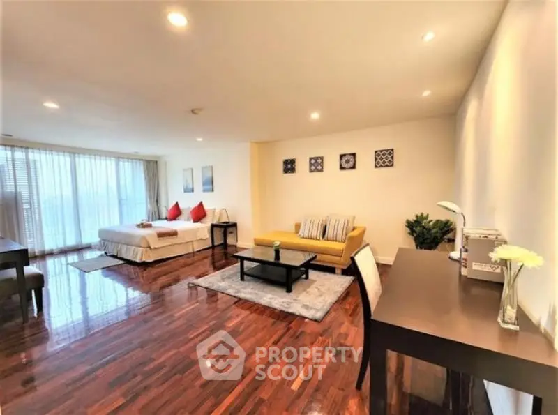 Spacious studio apartment with elegant wooden flooring and modern furnishings.