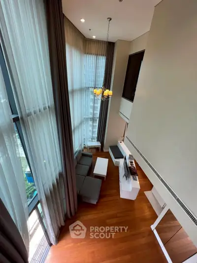 Luxurious high-ceiling living room with floor-to-ceiling windows and elegant decor.