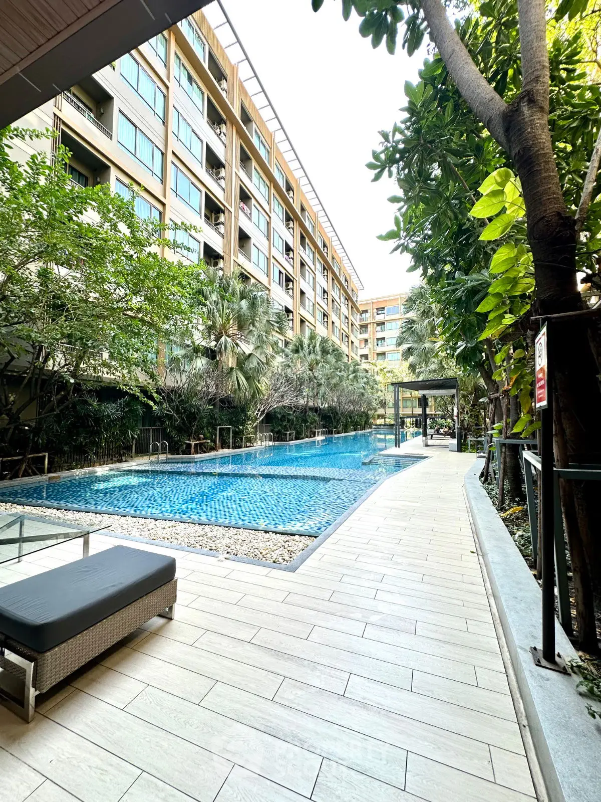 Luxurious condominium with stunning poolside view and lush greenery, perfect for relaxation and leisure.