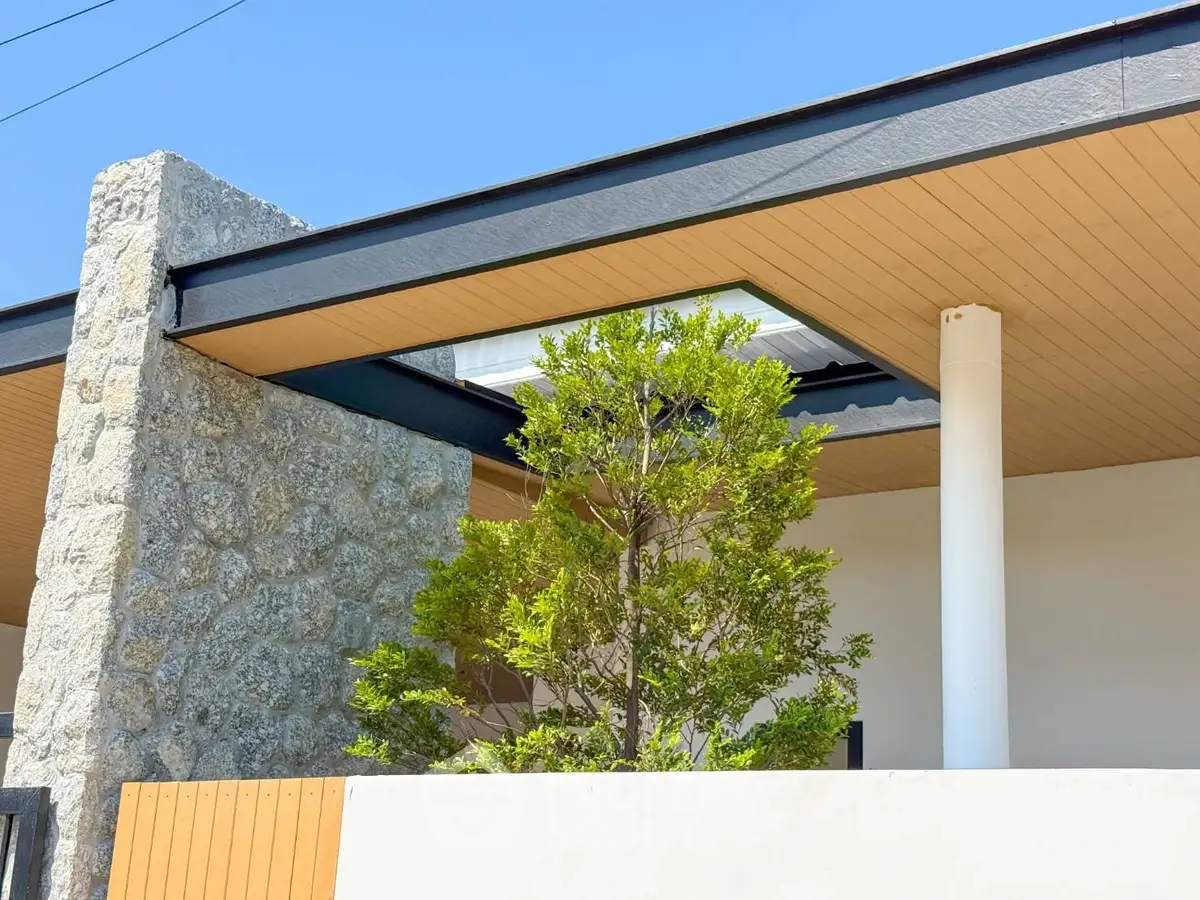 Modern architectural exterior with stone wall and sleek roof design.