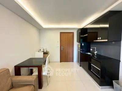 Modern kitchen with sleek black cabinets and dining area in open layout apartment.