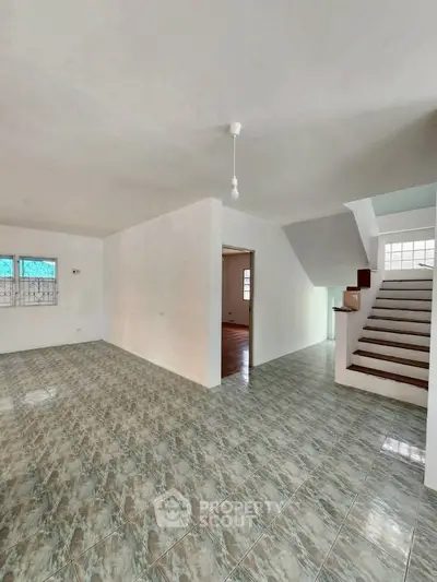 Spacious open-plan interior with tiled flooring and staircase, ideal for modern living.