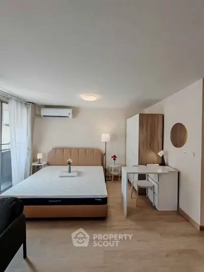 Modern bedroom with stylish decor and natural light, featuring a comfortable bed and workspace.