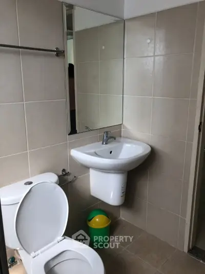 Modern bathroom with sleek fixtures and neutral tiles, featuring a wall-mounted sink and toilet.