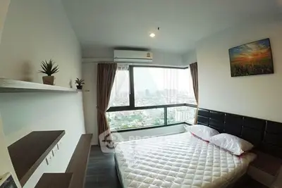 Modern bedroom with large window offering stunning city view, featuring sleek furniture and minimalist decor.
