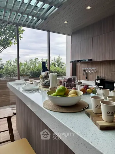 Modern kitchen with open layout and breakfast bar overlooking lush greenery.