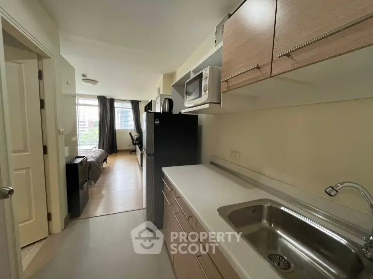 Modern apartment kitchen with sleek cabinetry and open layout leading to living area.