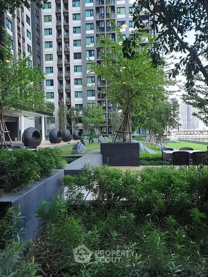 Modern residential building with lush garden and outdoor seating area.