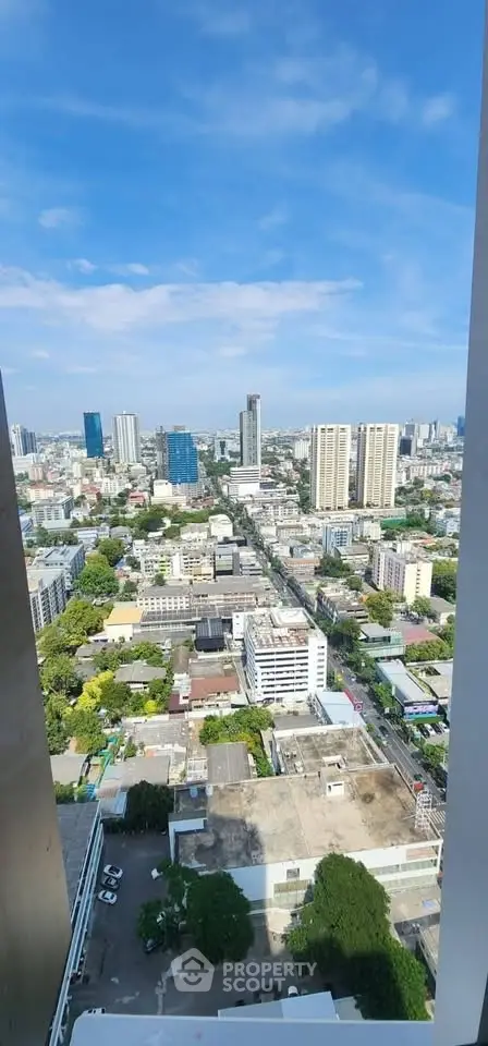 Stunning cityscape view from high-rise building balcony, showcasing urban skyline and blue sky.