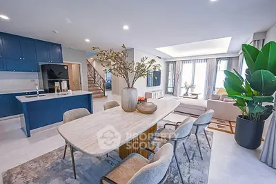 Spacious modern living room with open kitchen and elegant dining area, featuring stylish decor and natural light.