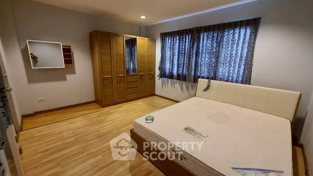 Spacious bedroom with wooden flooring and large wardrobe