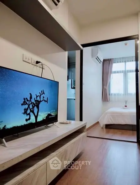 Modern apartment interior with cozy bedroom and stylish living area featuring a flat-screen TV.