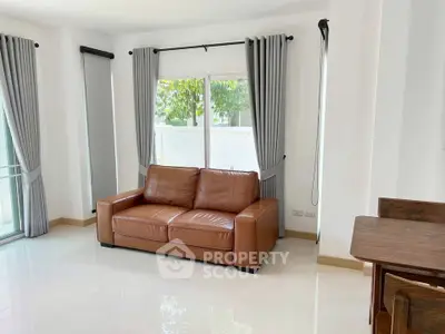 Spacious living room with leather sofa and large windows for natural light.