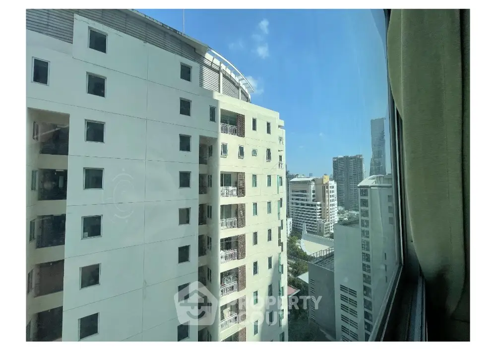 Stunning city view from high-rise apartment window showcasing urban skyline.