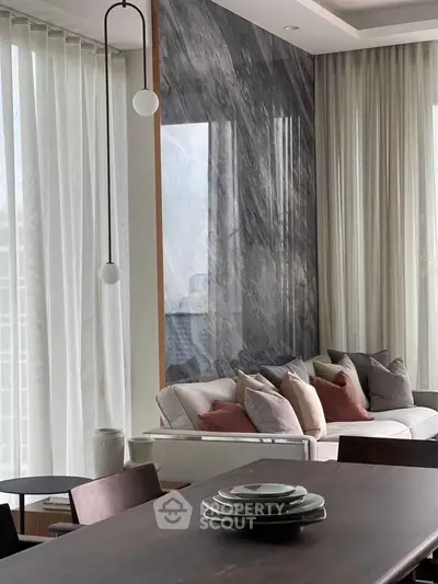Luxurious modern living room with elegant marble accent wall and plush seating, perfect for relaxation and entertaining.