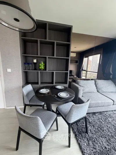 Modern living room with stylish furniture and city view, featuring a cozy dining area and elegant shelving.