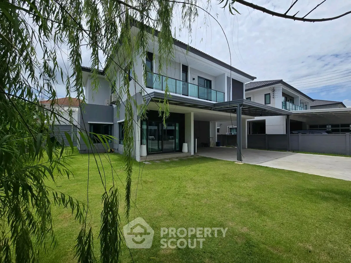 Modern two-story house with spacious lawn and sleek balcony design.