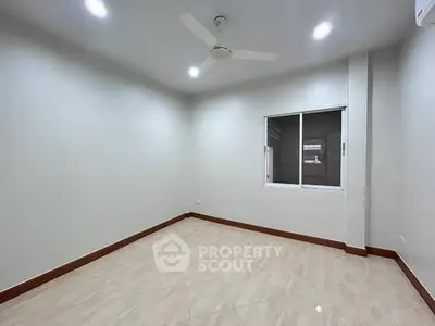 Spacious empty room with tiled flooring and ceiling fan, ideal for customization.