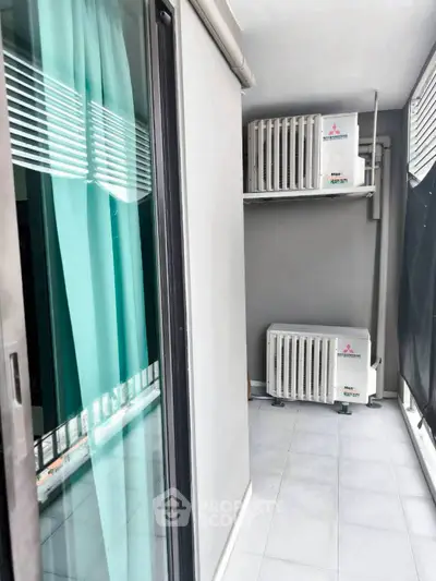 Modern balcony with air conditioning units and sleek glass doors in urban apartment.