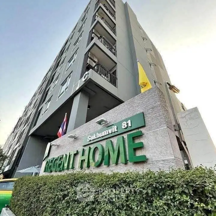 Modern condominium building exterior with prominent signage and lush greenery at Sukhumvit 81.