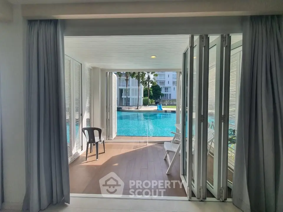 Luxurious poolside view from modern apartment with open balcony doors