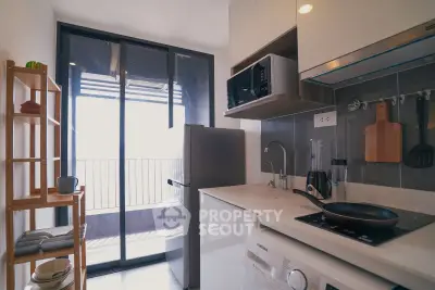 Modern kitchen with balcony view, featuring sleek appliances and ample natural light.
